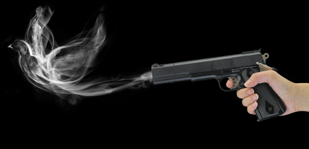 Hand holding a smoking gun isolated on blackの写真素材