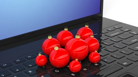 Xmas glass or plastic balls lying on laptop. Red decorative elements of different sizes.の写真素材