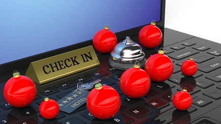 Christmas balls and hotel bell with check in tag and key, on laptop keyboardの写真素材