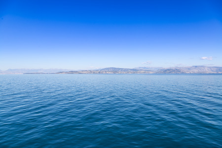 Blue sea waters and clear blue sky with distant land
