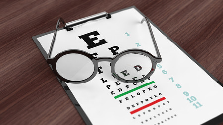 Eyeglasses on tablet with eyesight test on screen, set on wooden surface.