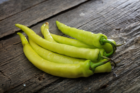 Stack of green chili peppers, on wooden surfaceの写真素材