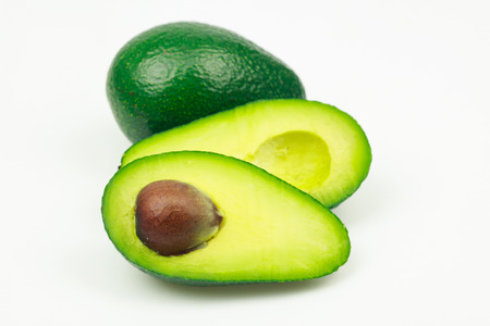 Avocado fruit and one cut in half with seed, on white background.
