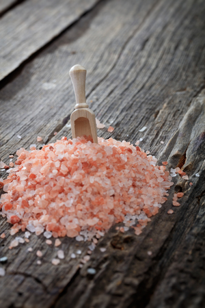 A heap of pink Himalayan salt, on wooden surface.