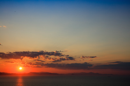 Melancholic scene of sundown over mountains and sea.の写真素材