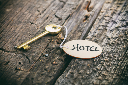 Round wooden tag with "Hotel" text on a key, wooden surfaceの写真素材