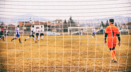 Goalkeeper behind a football goal netの写真素材