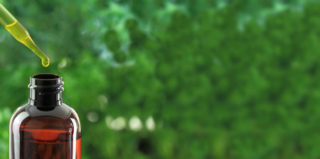 Dropper over essential oil bottle on green backgroundの写真素材
