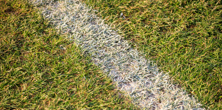 Above view to a white line on soccer field. Detail of white line in a football field.