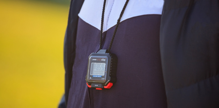 Coach with a stopwatch and blue tracksuit. Yellow background with space.