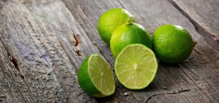 Cut and whole limes on wooden table, copy spaceの写真素材