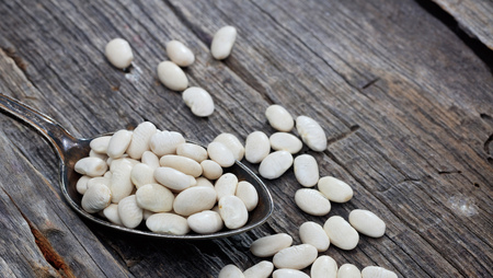 Raw white haricot beans  on an old wooden table, copy space