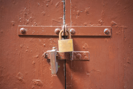 Wooden brown door background locked with two padlocks. Timeworn entrance provides safety and privacy. Close up view with details.の写真素材