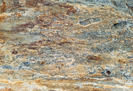 Grey brown stone wall background texture. Rocky cracked formation with holes, rough material. Abstract natural hard surface. Greek island Cyclades Greece.の写真素材