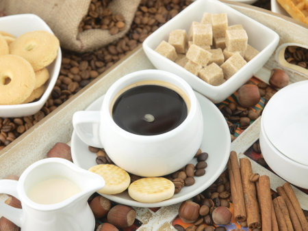 Coffee beans, sugar cubes, milk and cookies on a trayの写真素材