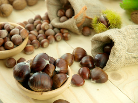 Fresh chestnuts in wooden bowl and jute bag on wooden backgroundの写真素材