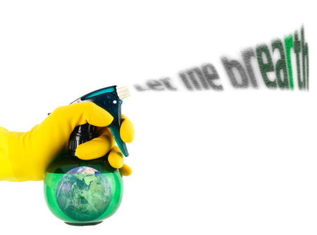Hand in yellow protective glove holding a spray bottle with detergent and globe isolated on white backgroundの写真素材