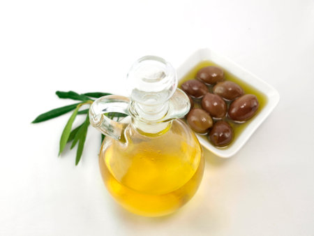 Olive oil in a glass bottle and olives on a white backgroundの写真素材
