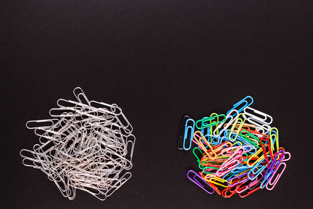 Color and gray groups of binder clips on black tableの写真素材