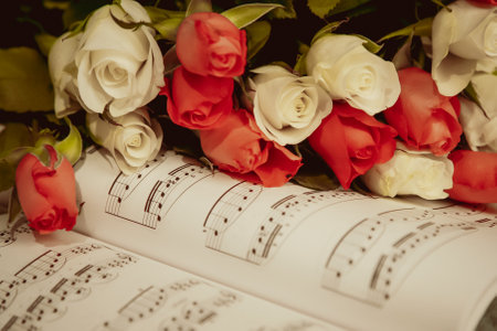 A book with a bunch of roses on top of it. The roses are pink and white. The book is open to a page...