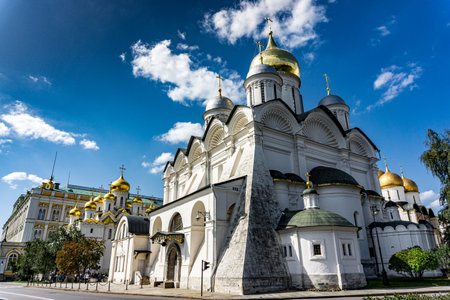 A white church in Kremlin in Moscow Russia with three domes and three crosses on top. The church is surrounded by treesの写真素材
