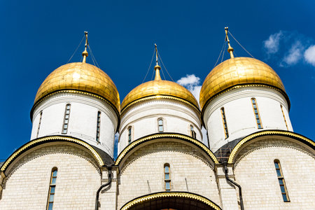 A building with a gold roof and a cross on top in Kremlin in Moscow Russia. The building is white. There are several windows on the buildingの写真素材