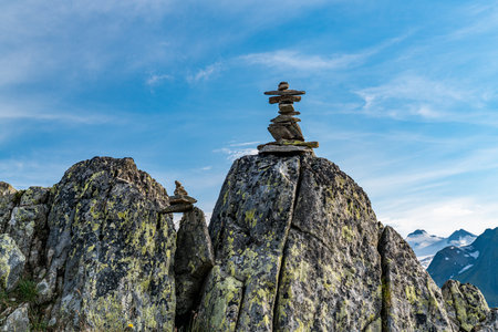 A rock with a cross on top of it. The sky is blue and clearの写真素材