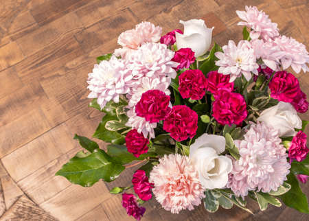 Top view of a pink and colorful bouquet, blossom flora with fresh green leaves at the wooden table, romantic surprise gift on an anniversary. Happy and love concept. Group of natural flower decorationの写真素材
