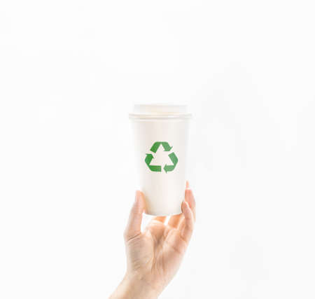 Personâs hand hold up a takeaway hot drink paper cup with green recycle symbol on white background. Concept idea of care, responsible, recycling and save the environment and globe from global warming.の写真素材