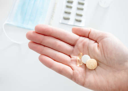 Hand holding vitamin tablets and pills for a healthy immune system, protection from spreading of...