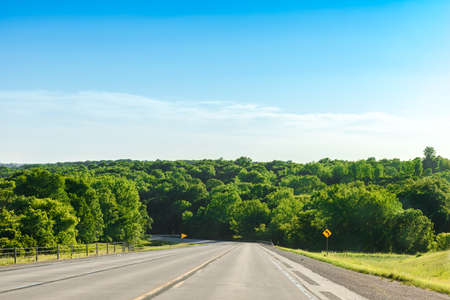 Scenic of greenery mountain, natural forest along with asphalt highway road with blue sky in spring and summer season. Long drive journey with green environment, road trip concept. Outdoor background.の写真素材