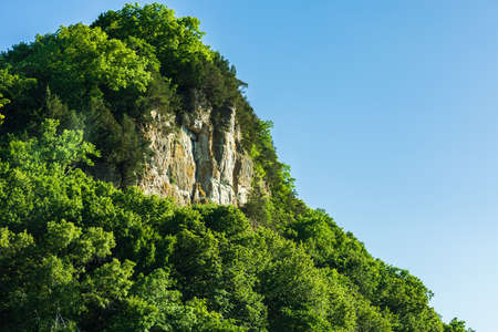 Scenic of greenery mountain with rocky wall area, natural lush forest against clear blue sky during seasonal. Beautiful freshness landscape, calmness and tranquility of green environment. Copy spaceの写真素材
