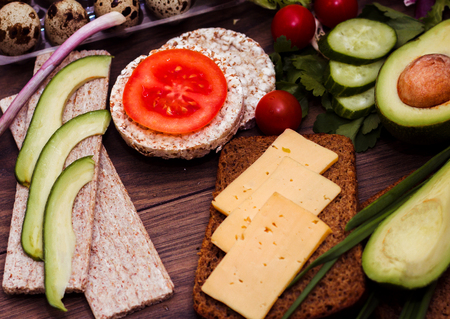 Slices of avocado on a wooden background, gluten-free bread, salad, green onions. Quail eggs. Healthy food. Vegetables and Vegetarian Food.の写真素材