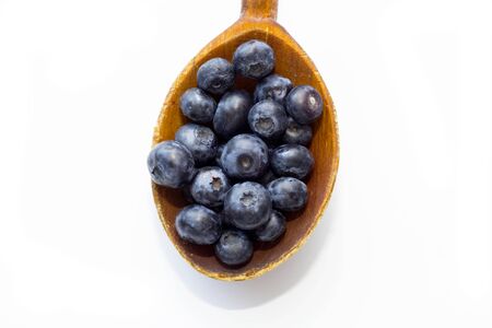 Blueberries in a wooden spoons isolated on a white background. White background with blueberries. Blueberry border design. Ripe and juicy fresh picked berries close up. Top view or flat lay.の写真素材