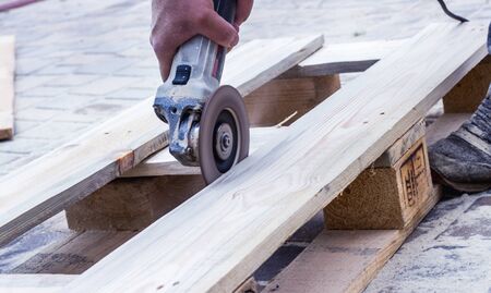 Workers hands at carpenter workspace refining the surface of wood board using sand paper grinder.の写真素材