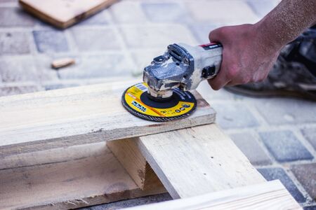 Restore old wooden planks with angle grinder. Close up of a carpenter and small buiness owner...