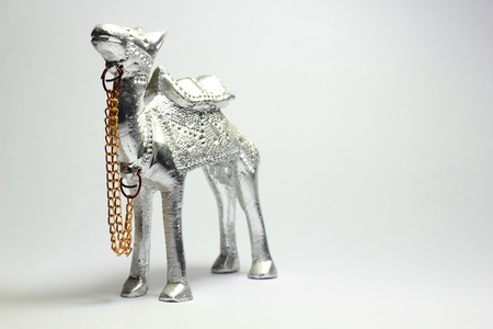 A camel made out of silver with a gold plated leash.の写真素材