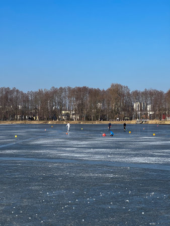 People play ice hockey on the frozen lake in the city park.の写真素材