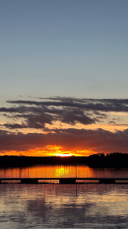 Sunset over the lake with silhouette of a man on the pierの写真素材