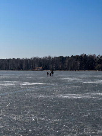 Winter landscape with frozen lake and people on the ice in the parkの写真素材