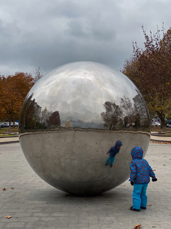 Child plays with a big sphere in the park on a cloudy day.の写真素材