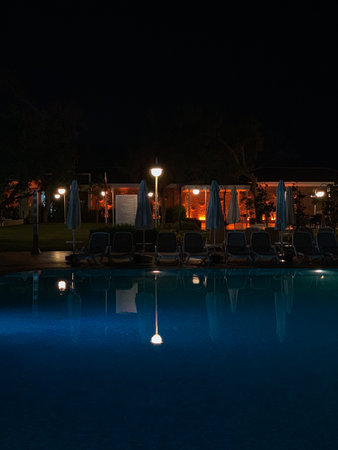 Swimming pool at night with sunbeds and umbrellasの写真素材