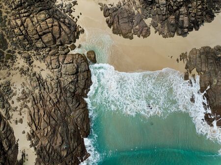 Aerial top down birds eye view of waves crashing onto a beachの写真素材