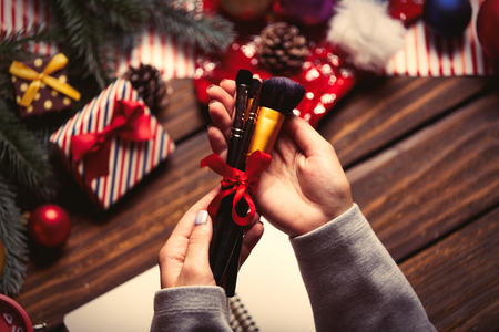 photo of the female hands holding brushes, notebook, alarm clock on the christmas decorations backgroundの写真素材