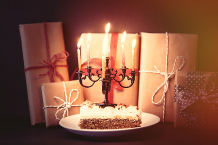Christmas candles and cake with gifts on background