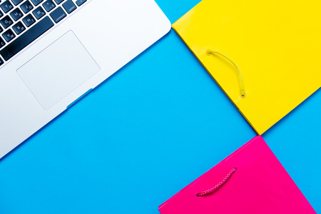 beautiful shopping bags and modern silver laptop on the wonderful blue backgroundの写真素材