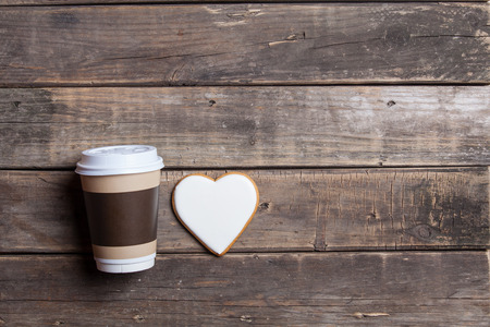 heart shaped cookie and cup of coffee on the wonderful brown wooden backgroundの写真素材