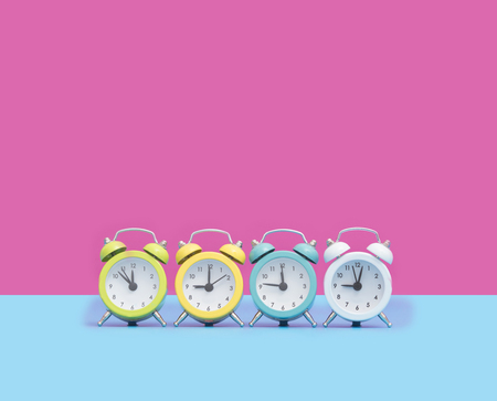 chain of cute colorful alarm clocks in front of wonderful pink backgroundの写真素材
