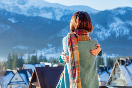 beautiful young woman hugging herself and looking at the splendid winter view in Polandの写真素材