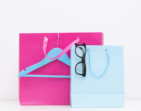 photo of cute shopping bags with glasses on one of them and hanger on the wonderful white background